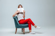 © Smeilov - Girl in red pants sitting in a chair and reading a book with a white cover