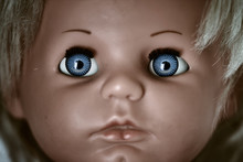 Creepy And Dark Doll's Head. A Scary Face Of A Blonde Baby Vintage Doll With Blue Eyes