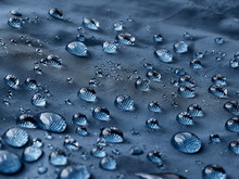 Rain Water Droplets On Blue Fiber Waterproof Fabric. Blue Background.