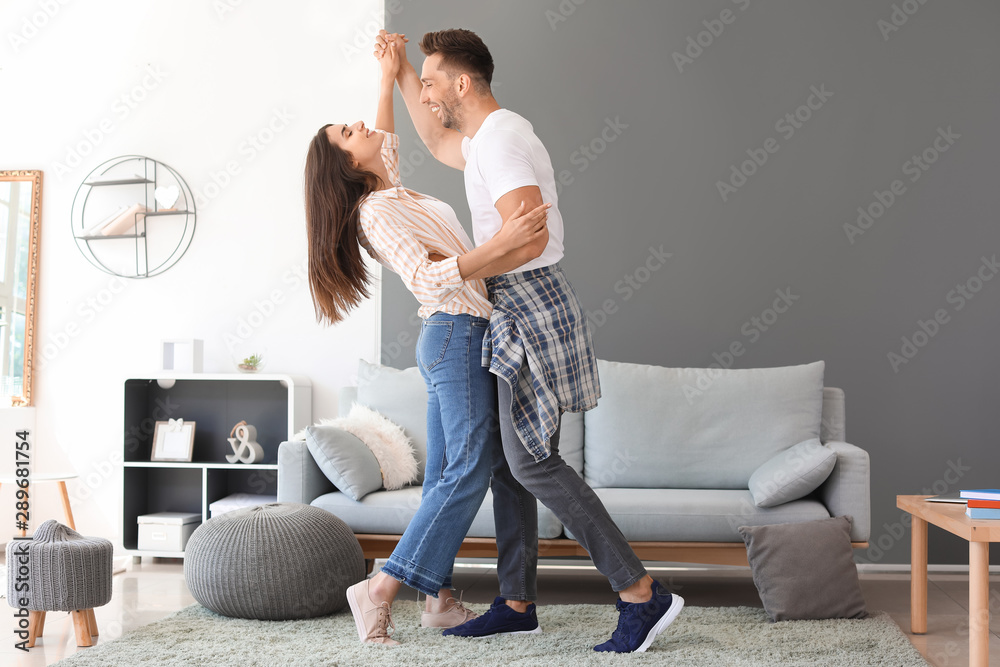 Happy young couple dancing at home - obrazy, fototapety, plakaty 