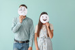 Couple hiding faces behind sheets of paper with drawn emoticons on color background