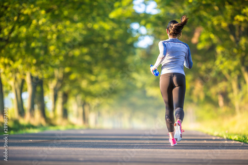 Cuadros en Lienzo Runner woman in autumn park tree alley training in sports thermal underwear
