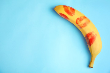 Wall Mural - Top view of fresh banana with red lipstick marks on blue background, space for text. Oral sex concept