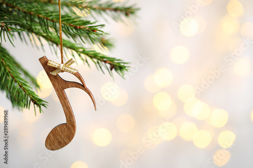 Fotomural Fir tree branch with wooden note against blurred lights, space for text