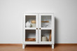 Wooden cabinet with kitchenware near white wall