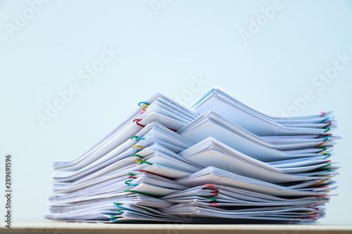 Fotografía Stack of document paper with colorful paperclip place on wooden table with copy space
