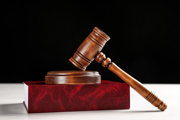 Judge's gavel and book on white table against black background. Criminal law concept