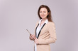 Successful ?aucasian positive elegant businesswoman in a beige jacket and holding a tablet in her hands posing on a purple background. Happy young woman advertises wholesales stores. Advertising space
