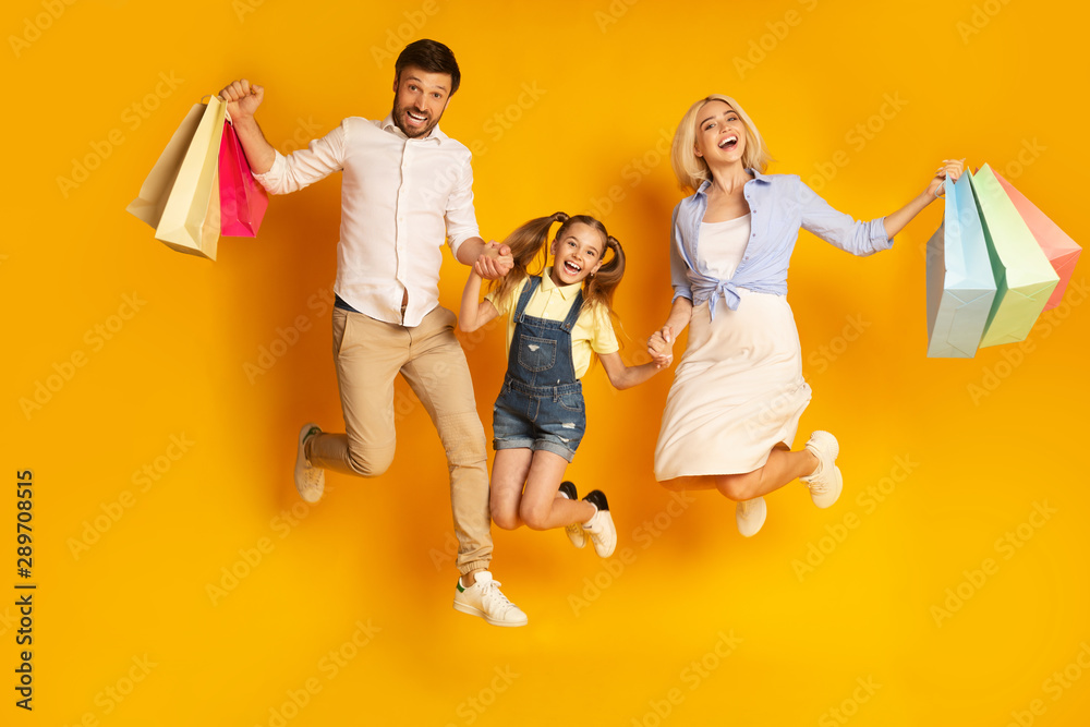 Happy Family Jumping Holding Shopping Bags Over Yellow Background - obrazy, fototapety, plakaty 