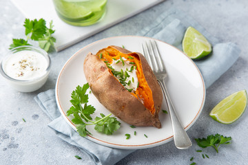 baked sweet potato with yogurt sausce on white plate