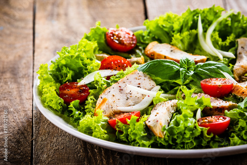 Cuadros en Lienzo Caesar salad on white plate on wooden table