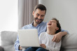 © fizkes - Cheerful dad and kid son laughing using laptop at home