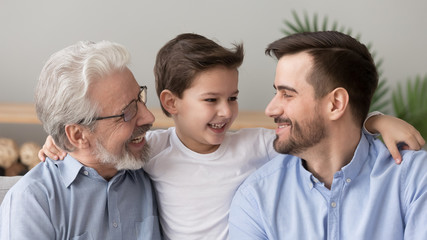 Wall Mural - Cute happy boy grandson embracing young father and old grandfather