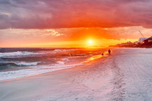 Couple Looking At Colorful Sunset In Santa Rosa Beach With Pensacola Coast In Florida Panhandle At Gulf Of Mexico Ocean Waves