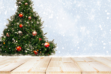 Wall Mural - top of empty wood table with beautiful christmas tree and snowfall backdrop. ready for your product 