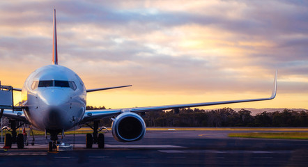 Sunset view of airplane on airport runway under dramatic sky in Hobart,Tasmania, Australia. Aviation technology and world travel concept.