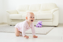 Adorable Baby Girl Learning To Crawl In White Sunny Room.