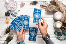 Fortune Teller Woman And A Blue Tarot Cards Over White Wooden Table Background.