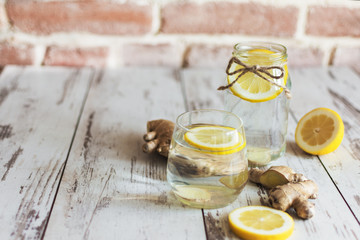 Wall Mural - Ginger with lemon detox water in the morning on wooden background.