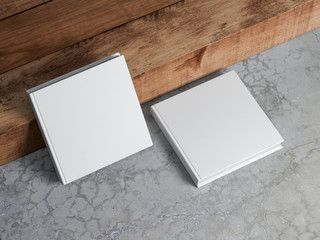 Two White square blank Books Mockup with textured hard cover on concrete floor near wood stair