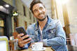 © goodluz - Trendy guy connected on smartphone at coffee shop