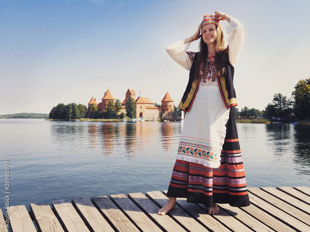 Obraz na płótnie Beautiful girl in national dress in an ancient medieval castle in Trakai in Lithuania. Retro photography. Restoring the atmosphere of the Middle Ages. w salonie