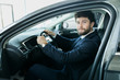 © F8  \ Suport Ukraine - Happy car owner at the dealership. Handsome young men sitting at front seat of the car looking at camera