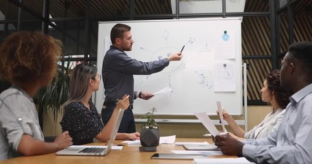 Wall Mural - Confident male speaker presenter pointing on whiteboard give presentation workshop