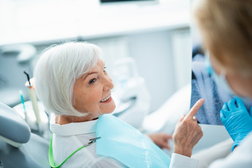 Wall Mural - Smiling adult lady sitting in dental chair