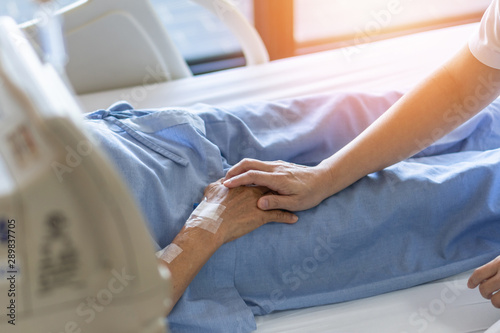 Fotografía Caregiver holding elderly senior patient (ageing old adult person) hand in hospi