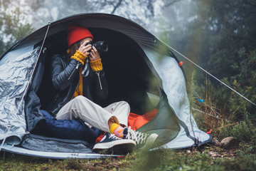 Wall Mural - photographer tourist traveler take photo on camera in camp tent in foggy rain forest, hiker woman shooting mist nature trip, trekking tourism, rest vacation concept camping holiday