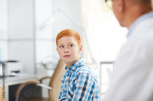 Portrait Of Cute Red Haired Kid Looking At Senior Doctor During