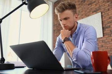 Poster - Young man using laptop at table indoors