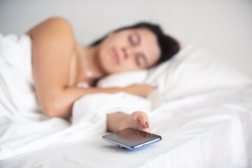 woman sleeping in bed phone in her hand