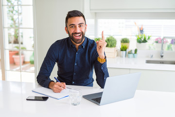 Sticker - Handsome hispanic man working using computer and writing on a paper surprised with an idea or question pointing finger with happy face, number one