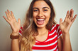 © Krakenimages.com - Young beautiful woman wearing red stripes t-shirt over white isolated background very happy and excited, winner expression celebrating victory screaming with big smile and raised hands