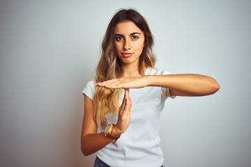 Sticker - Young beautiful woman wearing casual white t-shirt over isolated background Doing time out gesture with hands, frustrated and serious face