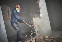 Demolition Work And Rearrangement. Worker With Sledgehammer Destroying Wall