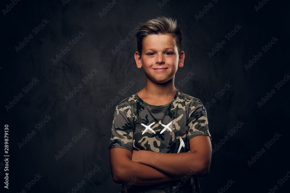 Little charming boy with nice hairstyle is posing over dark background at photo studio. - obrazy, fototapety, plakaty 