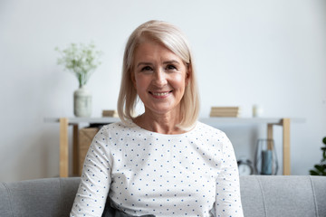 Head shot portrait smiling mature woman looking at camera