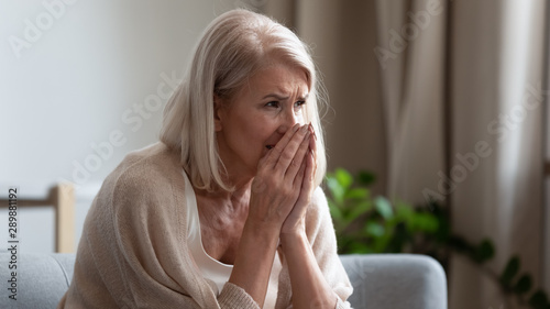 Upset mature woman crying, sitting alone, feeling lonely and unwell Tableau sur Toile