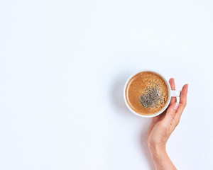 Wall Mural - White coffee cup in female hands on a white background. Top view