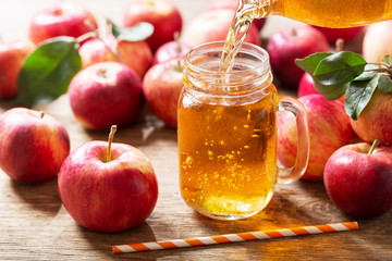 Wall Mural - apple juice pouring from bottle into glass jar