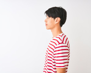 Wall Mural - Young chinese man wearing casual striped t-shirt standing over isolated white background looking to side, relax profile pose with natural face with confident smile.