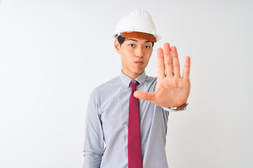 Poster - Chinese architect man wearing tie and helmet standing over isolated white background doing stop sing with palm of the hand. Warning expression with negative and serious gesture on the face.