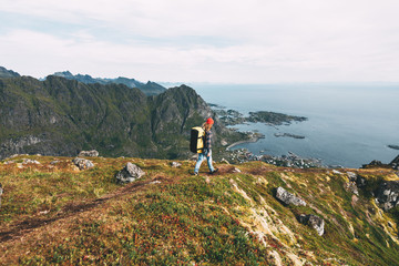 Wall Mural - Traveler man wearing backpack and red hat climb on high mountains above sea. Professional expeditor standing on the edge cliff rock and looking forward away. Wanderlust