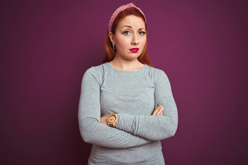 Sticker - Beautiful redhead woman wearing grey t-shirt and diadem over isolated purple background skeptic and nervous, disapproving expression on face with crossed arms. Negative person.