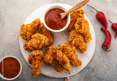 Fotomural Spicy chicken wings breaded with spices and ketchup on the table.