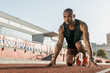 © InsideCreativeHouse - Low angle view of young man athlete in starting position for running on sports track