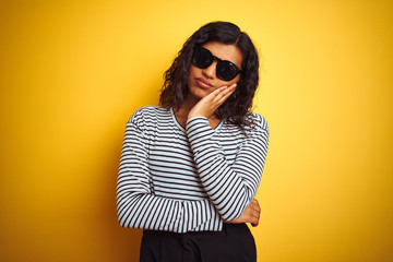 Wall Mural - Transsexual transgender woman wearing sunglasses over isolated yellow background thinking looking tired and bored with depression problems with crossed arms.